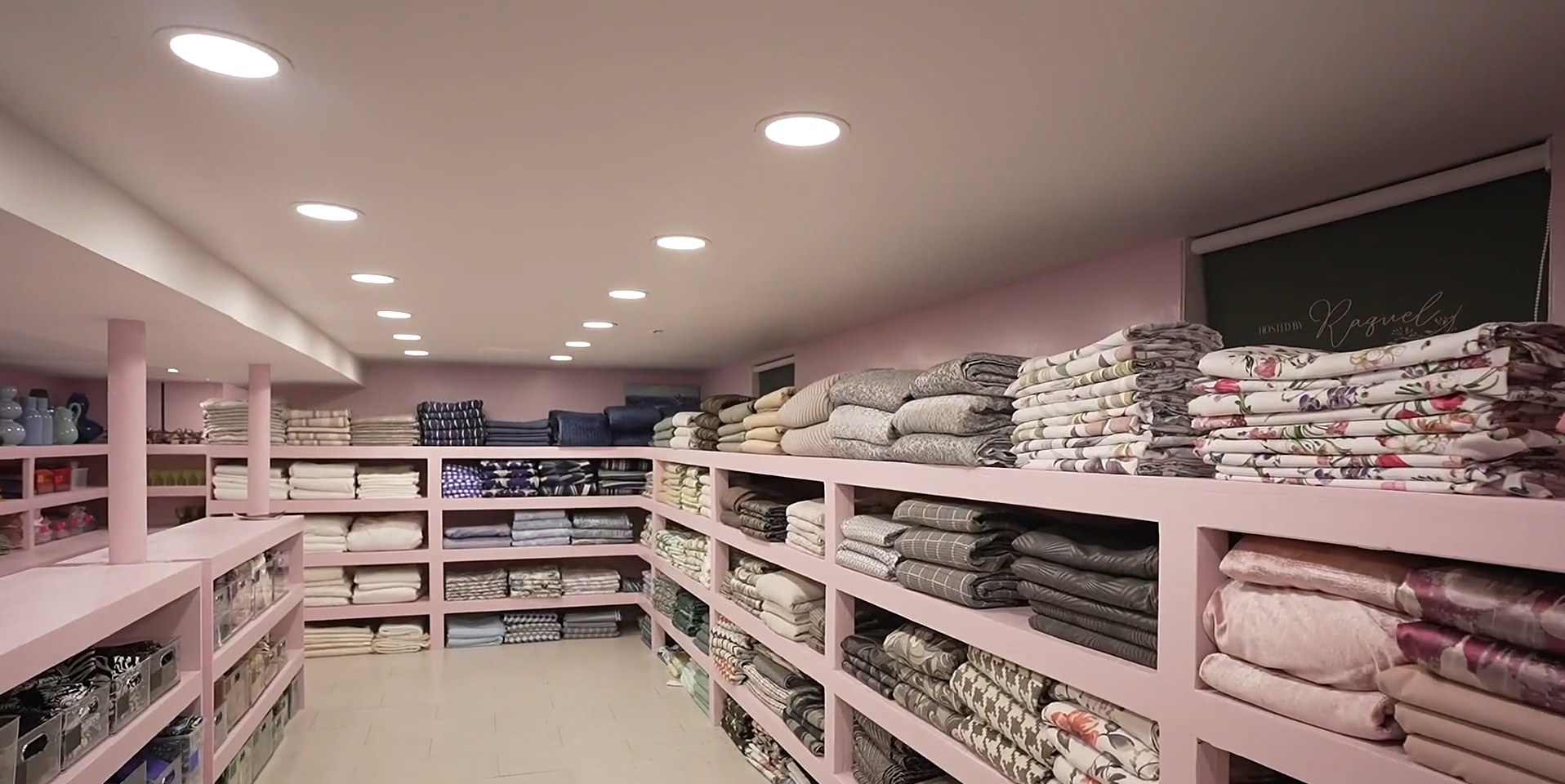 Inside the Hosted by Raquel gemach: pink shelves stacked with tablecloths and linens