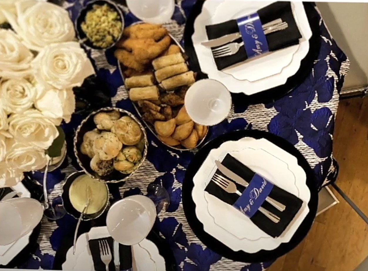 Overhead view of a table with a navy floral tablecloth, black napkins and white plates