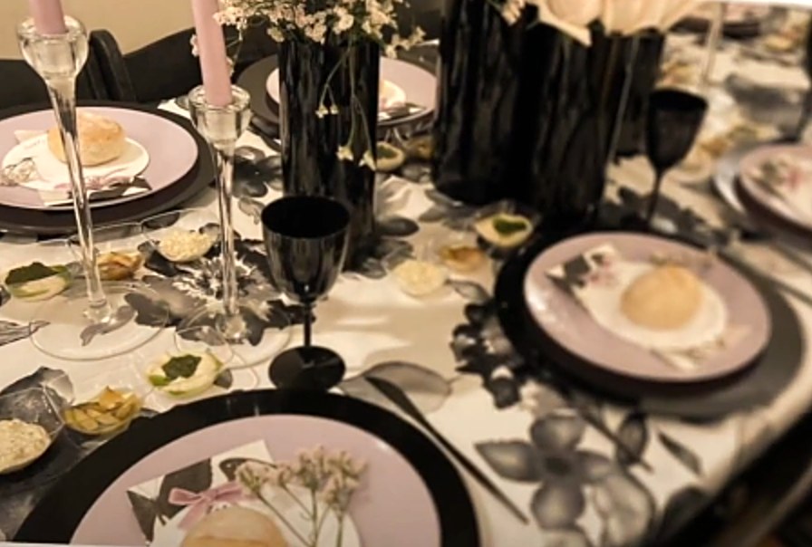 Table set with black chargers, blush plates and a black and white floral tablecloth